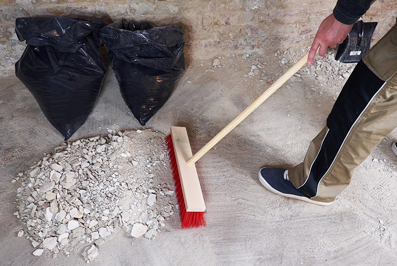 Workman sweeping the rubble with broom